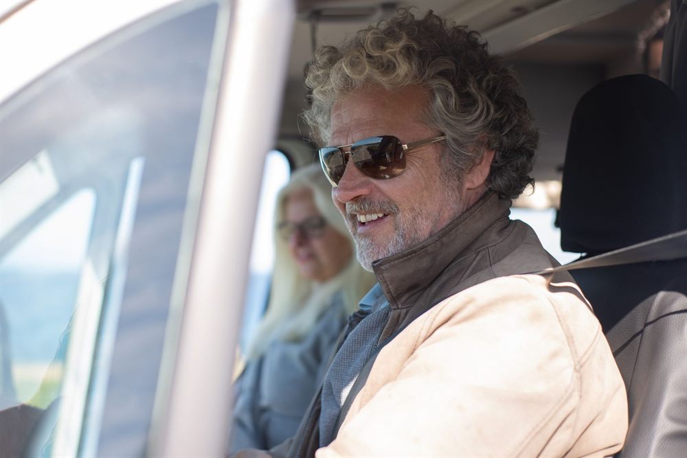 Smiling senior man driving on a road trip with his wife beside him
