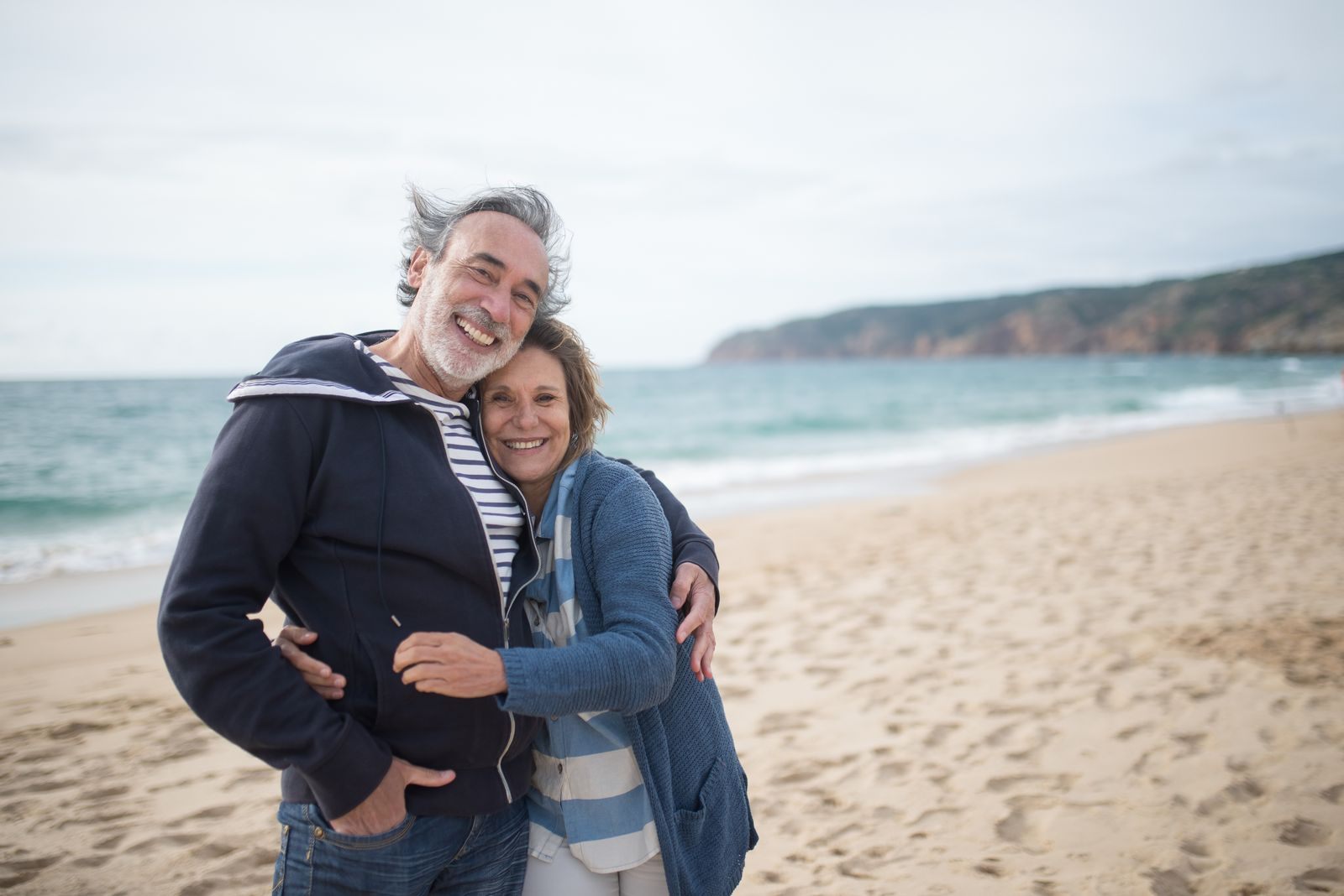 Senior couple embracing on a beach; AARP cruises are member offers for travelers 50 and over