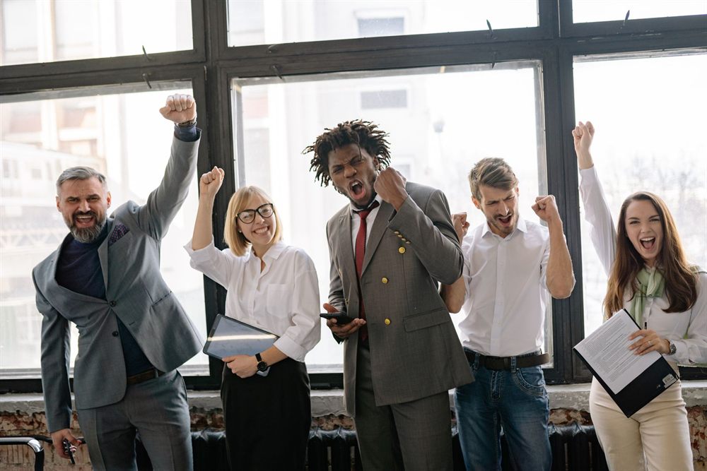 Colleagues cheering together beside a large office window