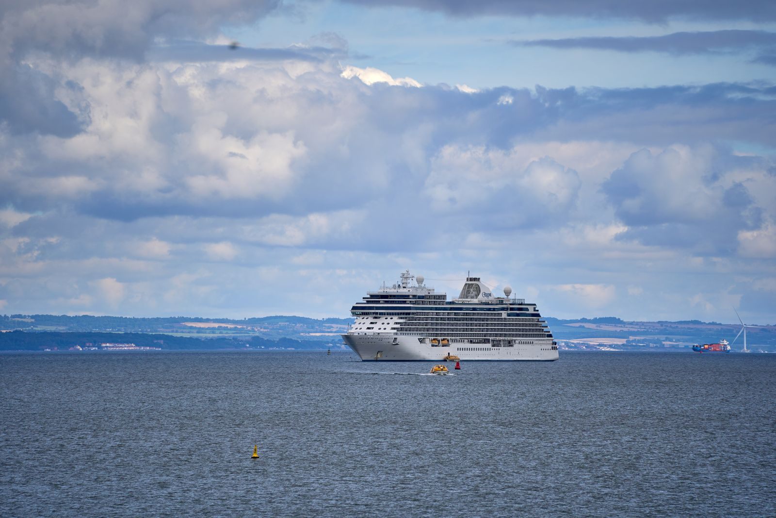 Member cruises: a cruise ship sailing on a calm sea under a cloudy sky